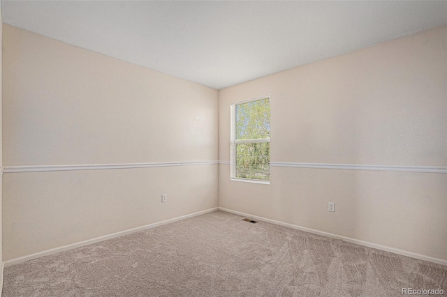 spare room featuring carpet floors, baseboards, and visible vents