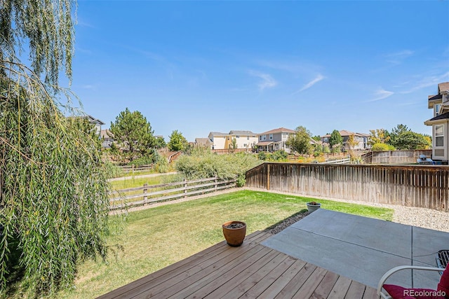 wooden deck featuring a lawn, a fenced backyard, a residential view, and a patio