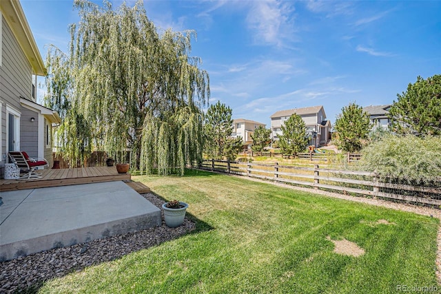 view of yard featuring a residential view, a wooden deck, a fenced backyard, and a patio area