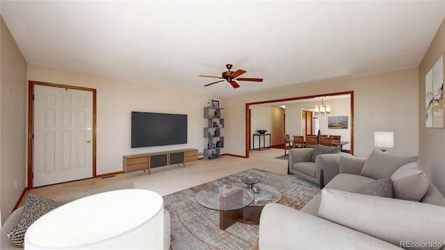 living room with light carpet, baseboards, and ceiling fan with notable chandelier