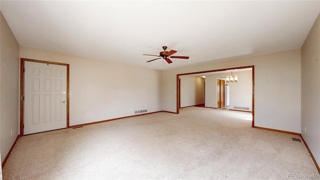 carpeted spare room with baseboards, visible vents, and ceiling fan with notable chandelier