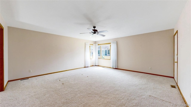 carpeted spare room with a ceiling fan, visible vents, and baseboards