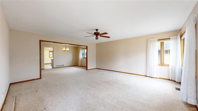 unfurnished room featuring baseboards, ceiling fan with notable chandelier, visible vents, and light colored carpet