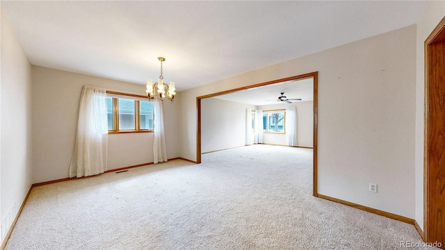 carpeted spare room with baseboards, a chandelier, and a wealth of natural light