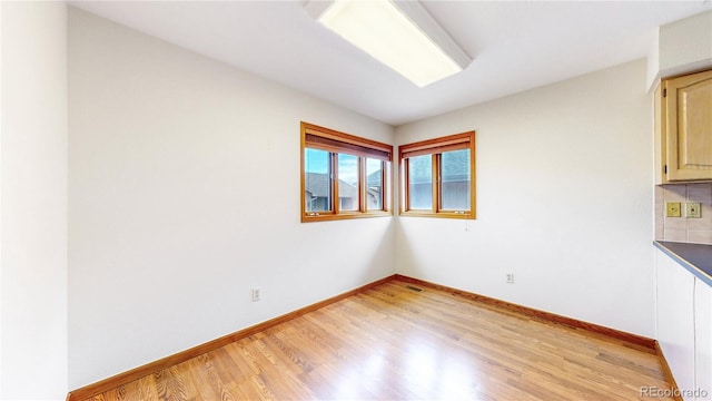 unfurnished room with light wood finished floors, visible vents, and baseboards