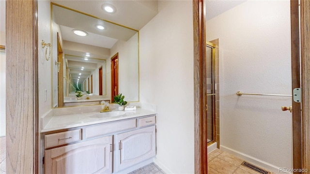 full bath with a shower stall, visible vents, baseboards, and vanity