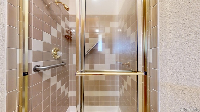 full bathroom featuring a shower stall and a textured wall