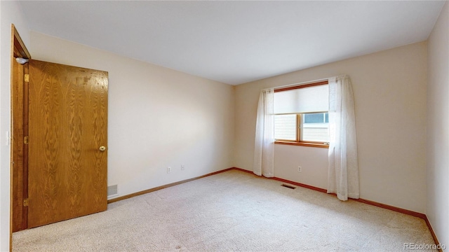 unfurnished room with carpet flooring, visible vents, and baseboards