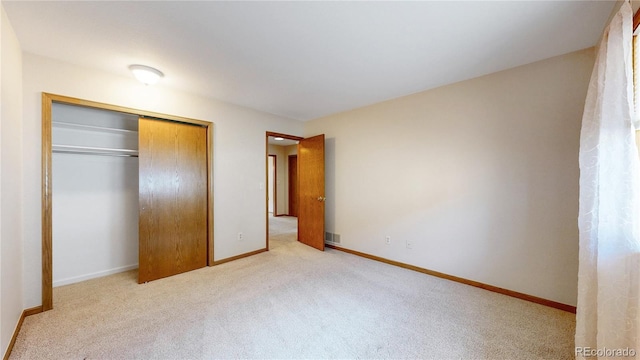 unfurnished bedroom featuring carpet, visible vents, baseboards, and a closet