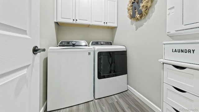 washroom with light hardwood / wood-style floors, cabinets, and washing machine and clothes dryer