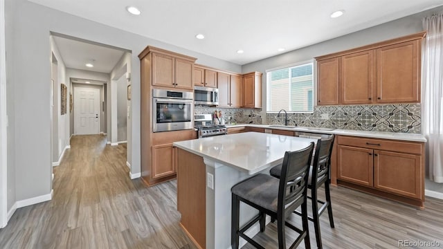 kitchen with sink, light hardwood / wood-style floors, a center island, and appliances with stainless steel finishes