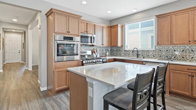 kitchen featuring sink, light wood-type flooring, a kitchen island, a breakfast bar area, and stainless steel appliances