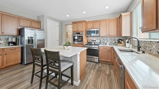 kitchen featuring wood-type flooring, appliances with stainless steel finishes, sink, a wealth of natural light, and a kitchen bar