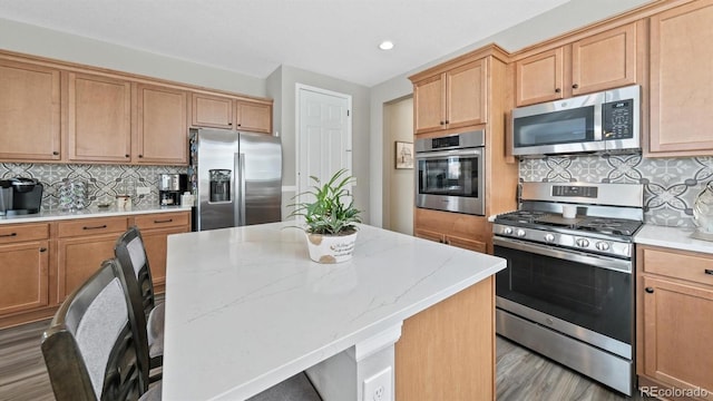 kitchen with a kitchen bar, tasteful backsplash, a center island, and appliances with stainless steel finishes