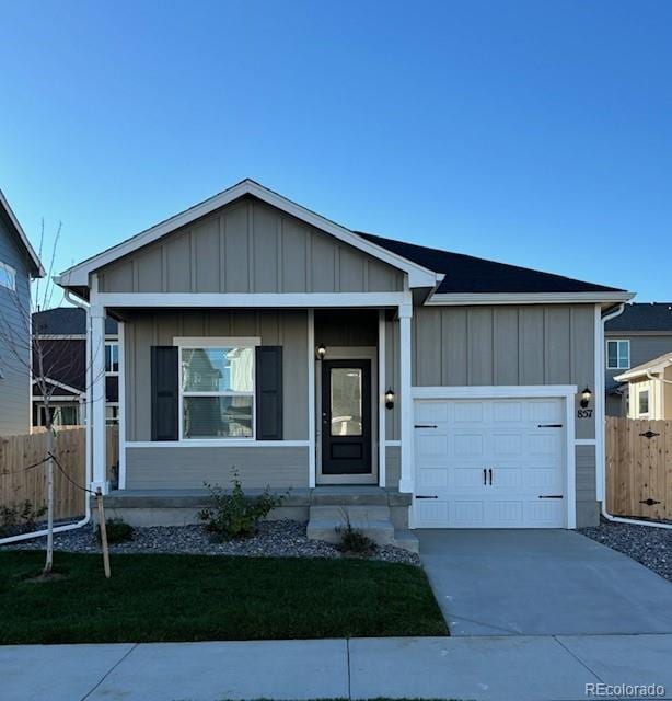 view of front facade with concrete driveway, board and batten siding, and fence