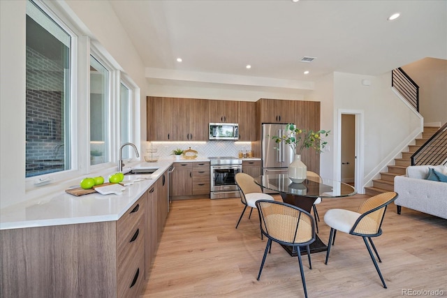 1372 Lowell Blvd Unit 1, Denver, CO 80204 - kitchen with appliances with stainless steel finishes, a sink, brown cabinets, light countertops, and tasteful backsplash