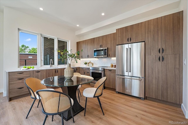 1372 Lowell Blvd Unit 1, Denver, CO 80204 - kitchen with appliances with stainless steel finishes, a sink, light wood-style floors, decorative backsplash, and light countertops