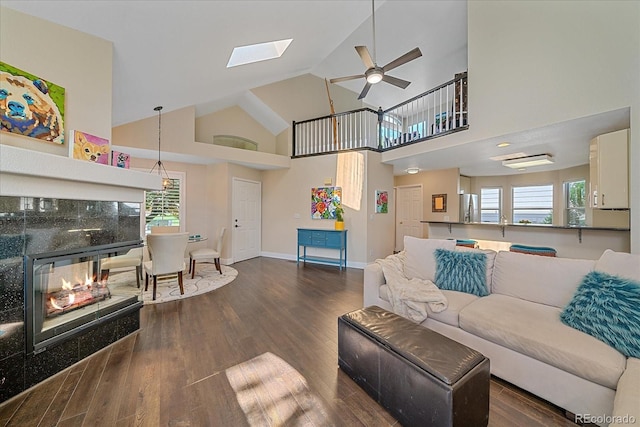 9346 W Coal Mine Ave, Littleton, CO 80123 - living area with a ceiling fan, wood finished floors, high vaulted ceiling, a tiled fireplace, and a skylight