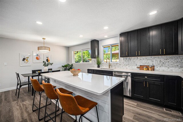 6032 Estes St, Arvada, CO 80004 - kitchen featuring dishwasher, dark cabinets, a kitchen breakfast bar, decorative backsplash, and dark wood-style flooring
