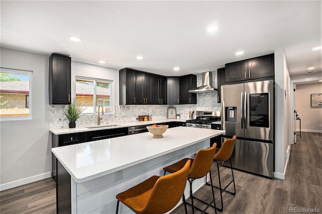 6032 Estes St, Arvada, CO 80004 - kitchen with appliances with stainless steel finishes, wall chimney range hood, decorative backsplash, dark wood-type flooring, and recessed lighting