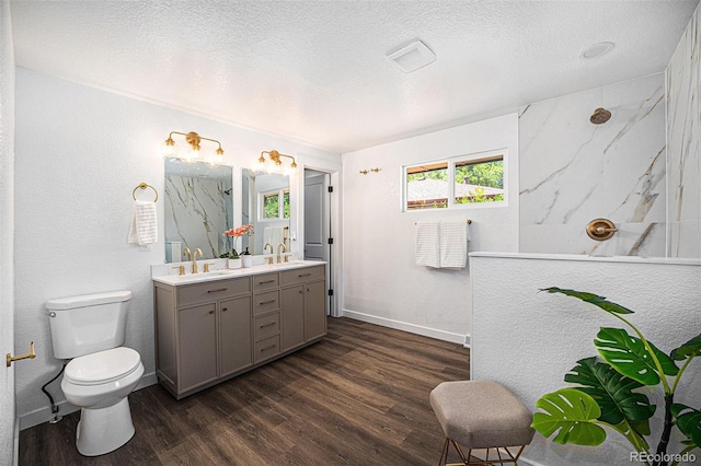 6032 Estes St, Arvada, CO 80004 - bathroom with double vanity, a marble finish shower, wood finished floors, healthy amount of natural light, and a textured ceiling