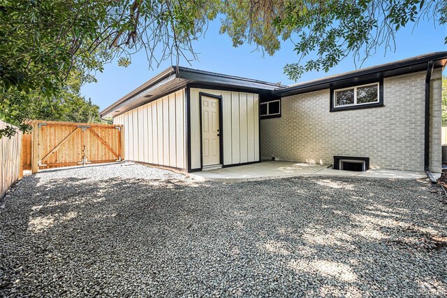 6032 Estes St, Arvada, CO 80004 - back of house with a gate, a patio, and brick siding