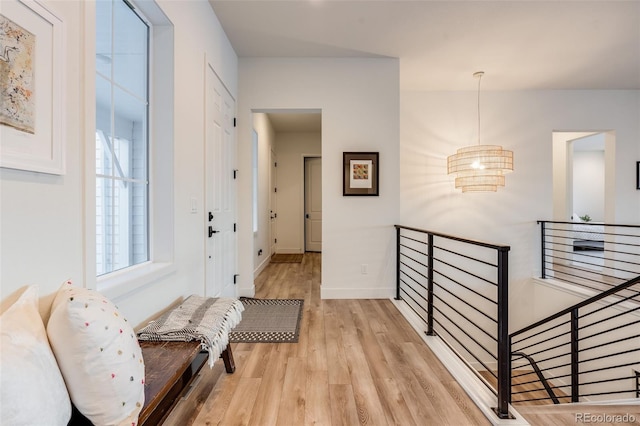 hall featuring an inviting chandelier and light wood-type flooring