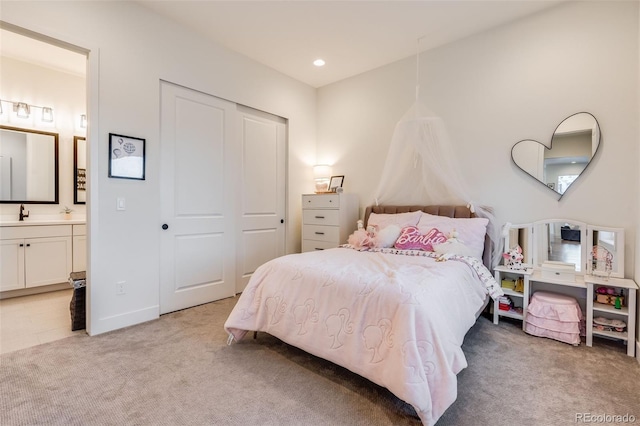 bedroom featuring sink, ensuite bathroom, a closet, and light carpet