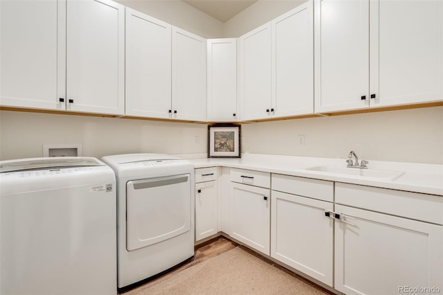 clothes washing area with sink, cabinets, and independent washer and dryer