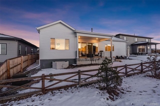 snow covered rear of property featuring a porch