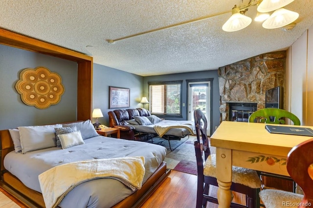 bedroom with wood-type flooring, a textured ceiling, and a fireplace