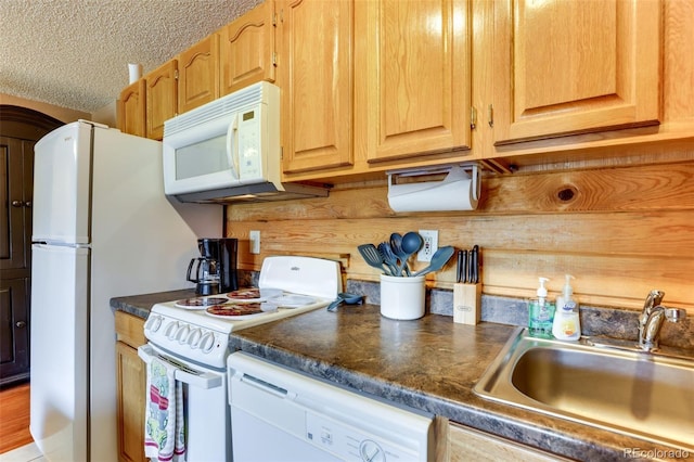 kitchen featuring white appliances, wood walls, a textured ceiling, and sink