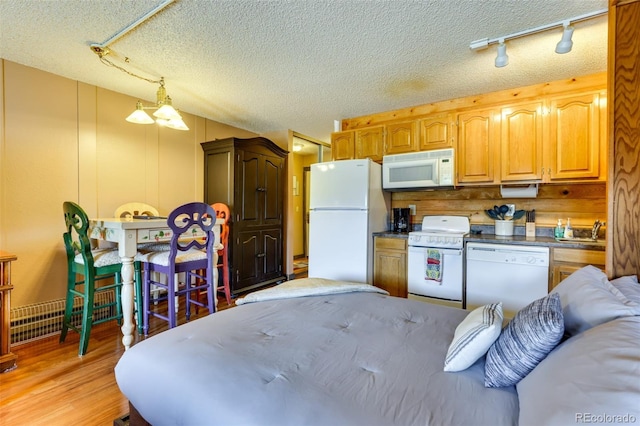 kitchen featuring light hardwood / wood-style floors, white appliances, a textured ceiling, and decorative light fixtures