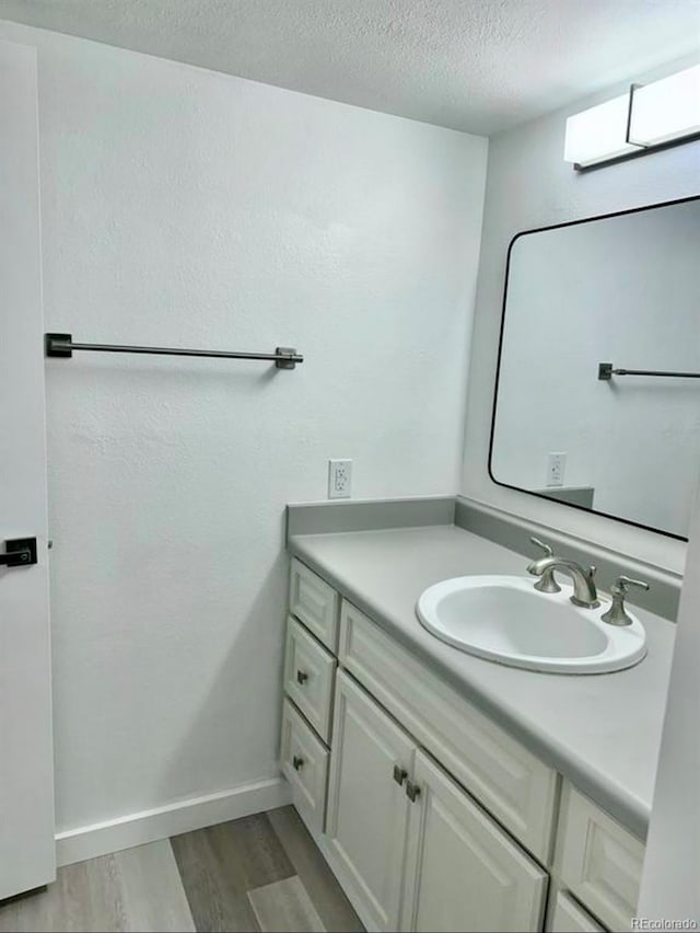 6480 S Dayton St Unit M04, Englewood, CO 80111 - bathroom featuring wood finished floors, vanity, and a textured ceiling