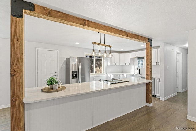 kitchen with dark wood-type flooring, stainless steel fridge with ice dispenser, decorative light fixtures, light stone counters, and white cabinetry