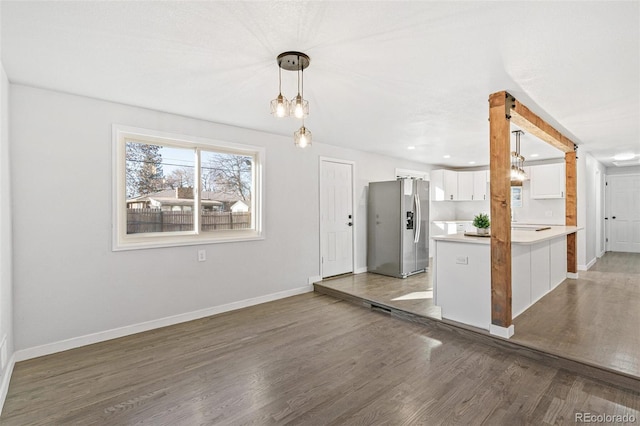 kitchen featuring pendant lighting, white cabinets, dark hardwood / wood-style floors, stainless steel fridge, and kitchen peninsula