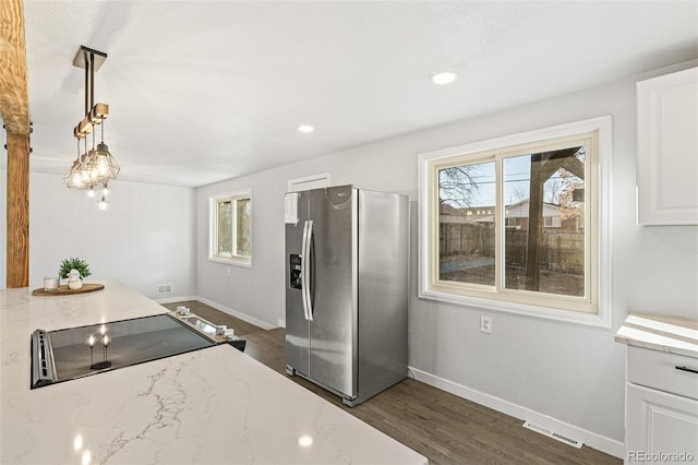 kitchen with dark wood-type flooring, hanging light fixtures, stainless steel fridge with ice dispenser, light stone counters, and white cabinets