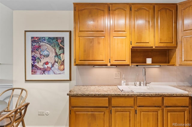 9320 E Center Ave Unit 4B, Denver, CO 80247 - kitchen featuring decorative backsplash, light stone counters, a sink, brown cabinetry, and open shelves