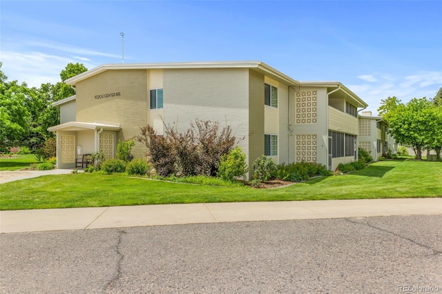 9320 E Center Ave Unit 4B, Denver, CO 80247 - view of property exterior featuring a lawn, brick siding, and driveway