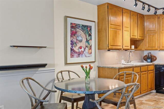9320 E Center Ave Unit 4B, Denver, CO 80247 - kitchen featuring a sink, backsplash, brown cabinetry, black dishwasher, and light stone counters