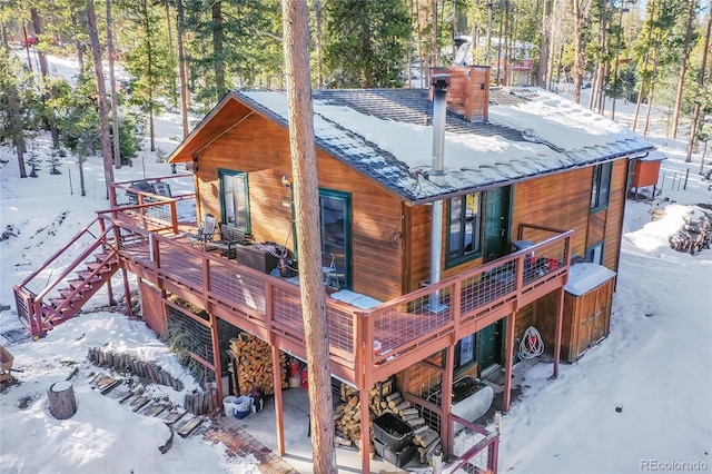 snow covered back of property with a wooden deck