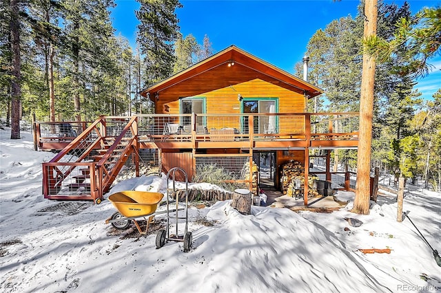 snow covered house featuring a wooden deck