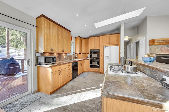 kitchen with sink, tasteful backsplash, tile countertops, vaulted ceiling with skylight, and black appliances