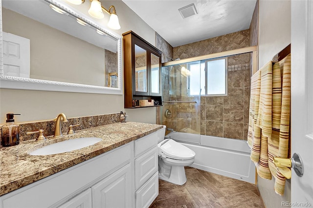 full bathroom featuring vanity, bath / shower combo with glass door, and toilet