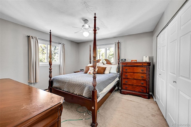 carpeted bedroom with multiple windows, ceiling fan, a closet, and a textured ceiling