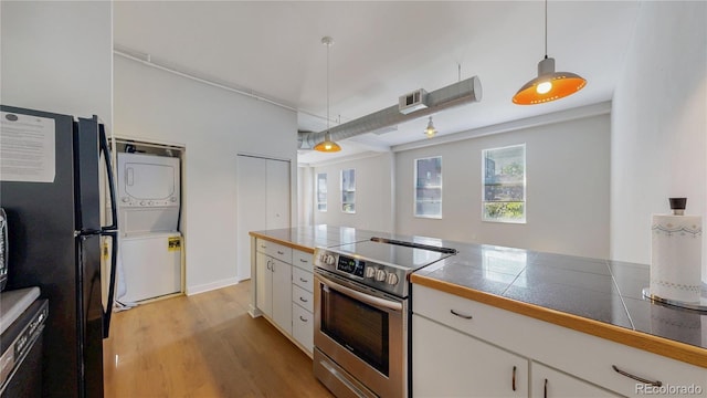 1521 Central St Unit 2D, Denver, CO 80211 - kitchen featuring stainless steel electric range oven, stacked washing machine and dryer, white cabinets, and hanging light fixtures
