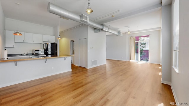 1521 Central St Unit 2D, Denver, CO 80211 - kitchen with stainless steel microwave, freestanding refrigerator, a breakfast bar, open floor plan, and light wood-style flooring