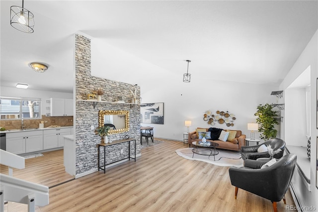 living room with a fireplace, sink, vaulted ceiling, and light wood-type flooring