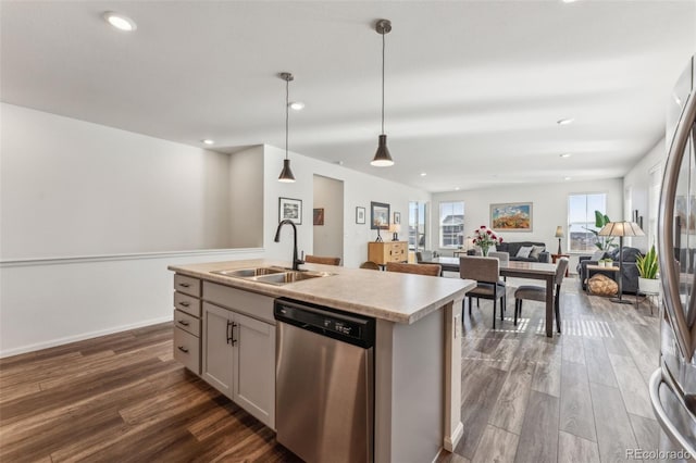 kitchen with open floor plan, stainless steel appliances, dark wood-type flooring, and a sink