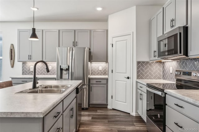 kitchen with stainless steel appliances, a sink, light countertops, and gray cabinetry